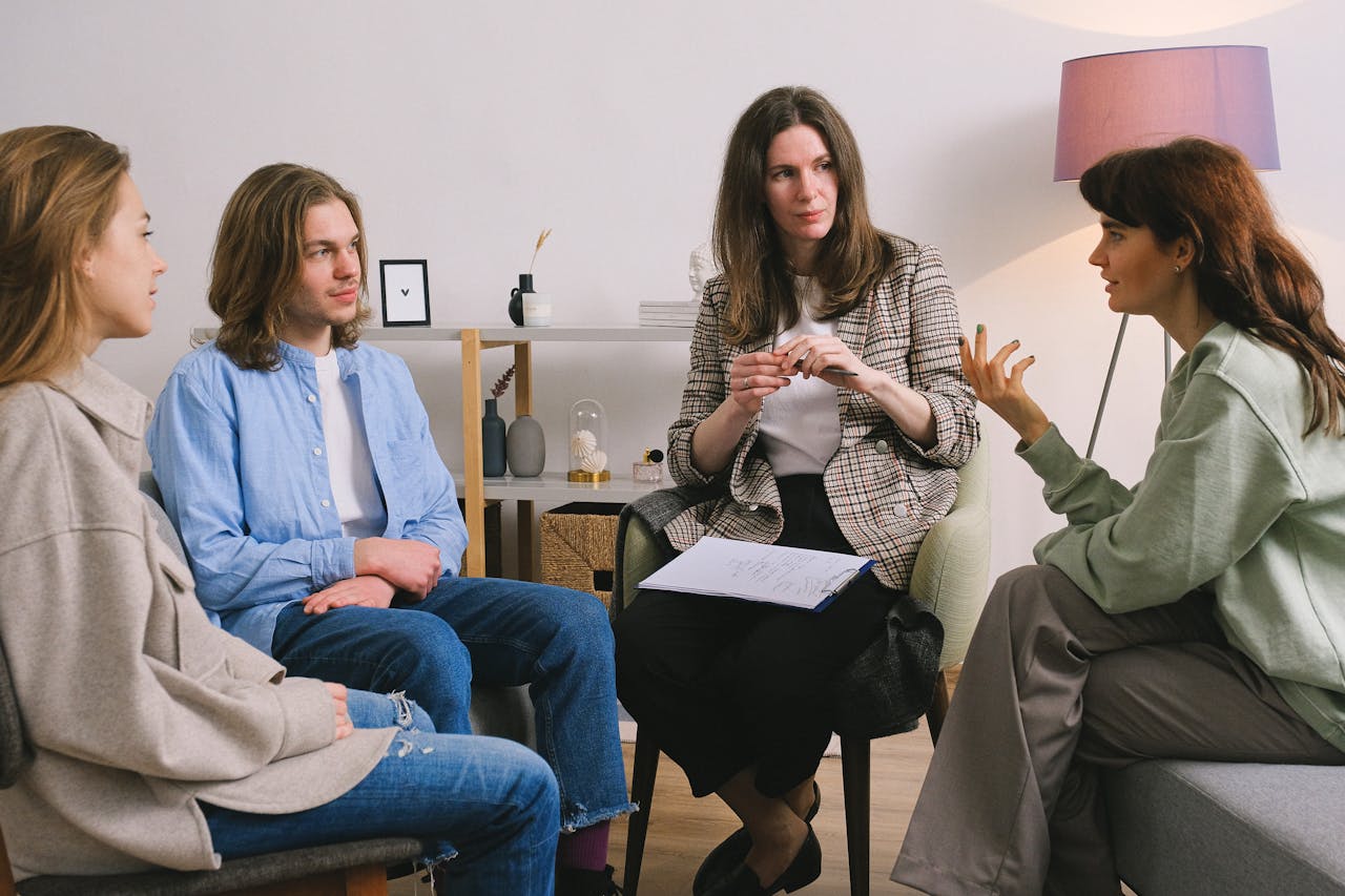A group therapy session taking place indoors with an attentive counselor guiding the discussion.